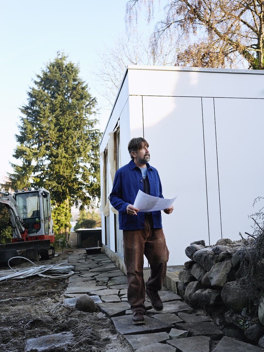Iemand loopt met de tekeningen in de hand langs een complex